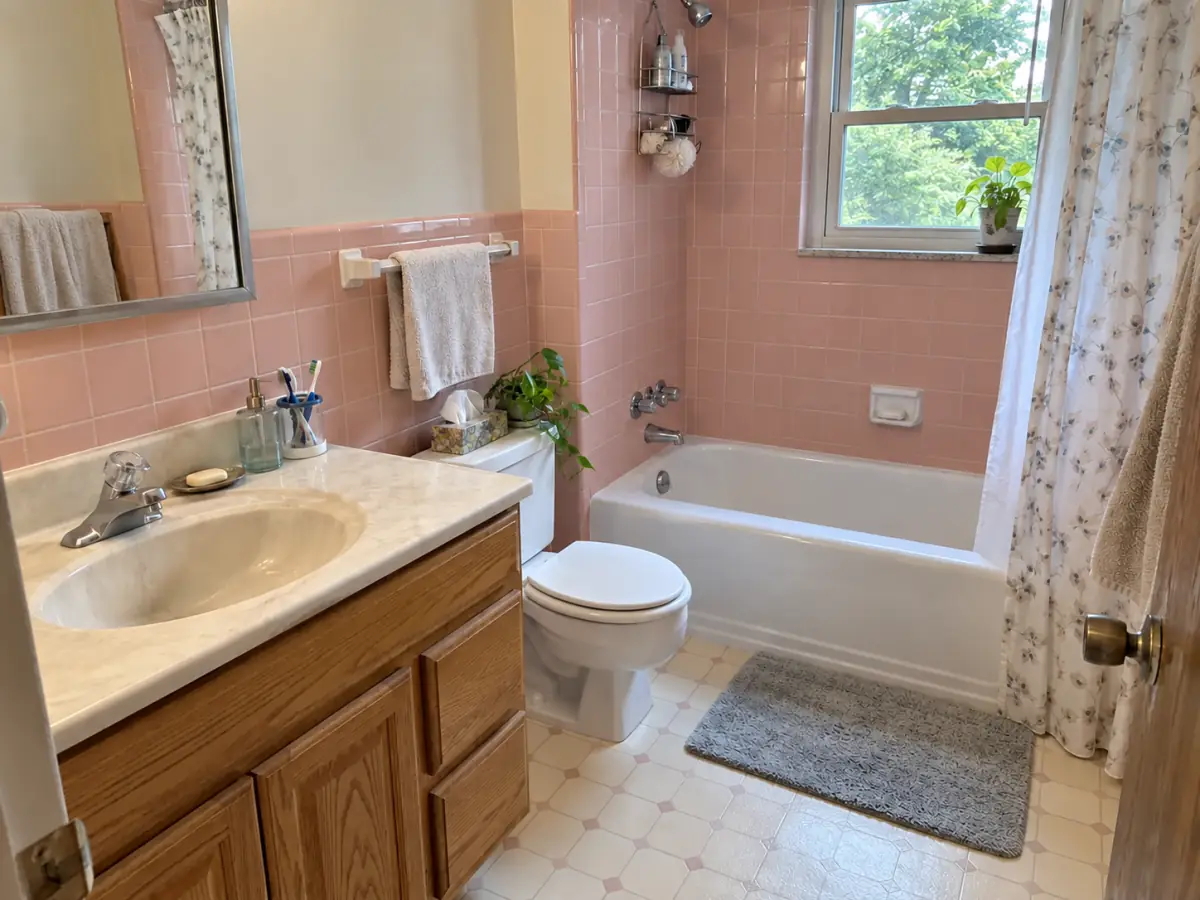 dated 1980s bathroom with pink tile and oak vanity, before AI redesign