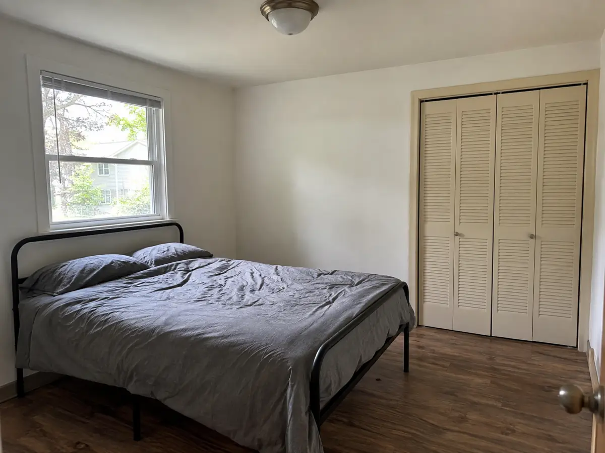 bare guest bedroom with metal bed frame, before AI redesign